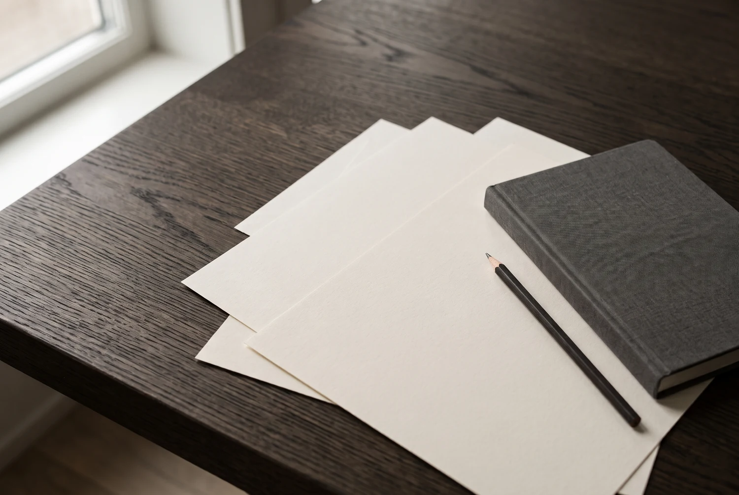 Notebook, pencil, and papers arranged on an oak working table